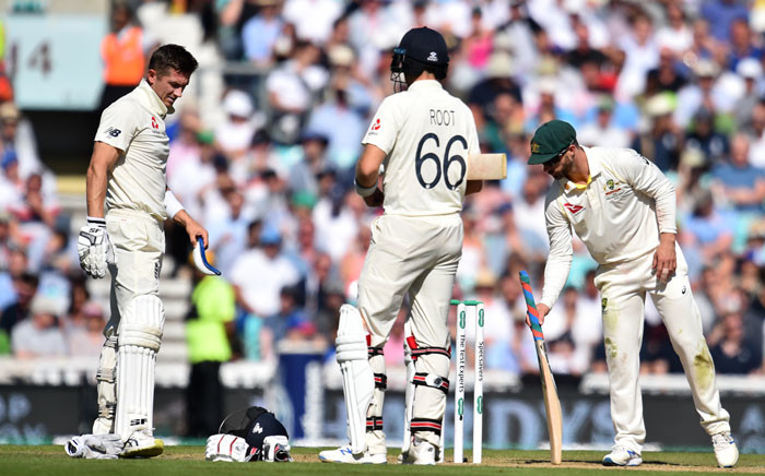 England's Joe Denly (L) gestures after being hit by a ball in the midriff as England's captain Joe Root (C) looks on during play on the third day of the fifth Ashes cricket Test match between England and Australia at The Oval in London on 14 September 2019.