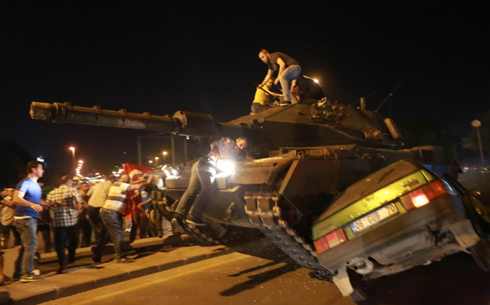 A tank crashes against a car as people take to the streets in Ankara, Turkey, during a protest against a military coup. Picture: AFP.