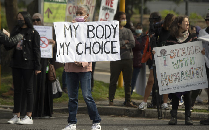 FILE: Demonstrators hold up banners and placards during a protest against COVID-19 vaccinations in front of Groote Schuur Hospital in Cape Town on 21 August 2021.Picture: Rodger Bosch/AFP