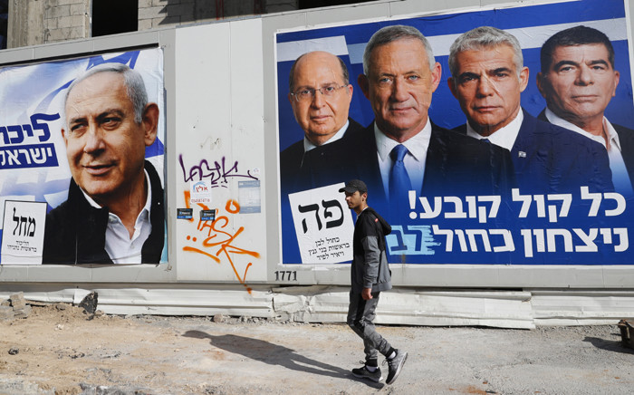 FILE: A man walks past electoral campaign posters bearing the portraits of Israel's Prime Minister Benjamin Netanyahu (L), leader of the Likud party, and retired Israeli general Benny Gantz (R), one of the leaders of the Blue and White (Kahol Lavan) political alliance, in the Israeli city of Tel Aviv, on 3 April 2019, ahead of the general election scheduled for 9 April. Picture: AFP
