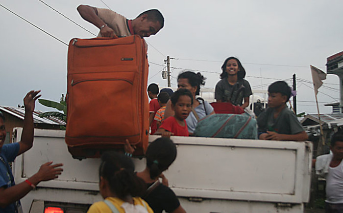 Residents carry their belongings onto a government vehicle as they evacuate from their tent houses to a safer place in Tacloban City, central Philippines on 4 December 4, 2014, ahead of the landfall of super Typhoon Hagupit. Picture: AFP.