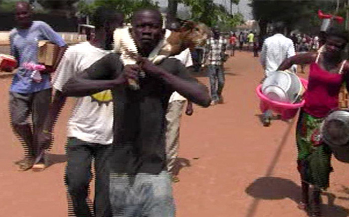 FILE: A video grab made on March 24, 2013 shows suspected looters carrying goods as they walk in a street in Bangui on March 24, 2013. Rebels seized control of Bangui and the coup-prone country's president disappeared. Picture: AFP