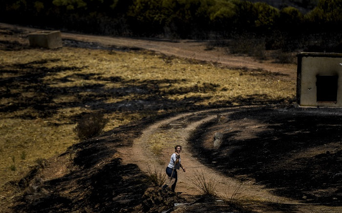 A woman carries a shovel in a field burnt overnight during a wildfire at Santa Rita in Tavira, south of Portugal, on August 17, 2021. Picture: Patricia De Melo Moreira / AFP. 