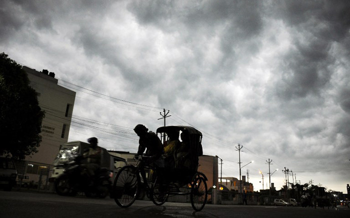 An Indian rickshaw puller transports passengers as storm clouds cover the sky over Agartala, capital of the northeastern state of Tripura, on 5 April, 2015. Picture: AFP.