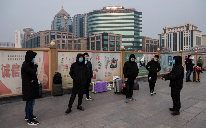 People wearing protective masks to help stop the spread of a deadly virus which began in Wuhan, wait next to their suitcases at the Beijing railway station in Beijing on 27 January 2020. Picture: AFP