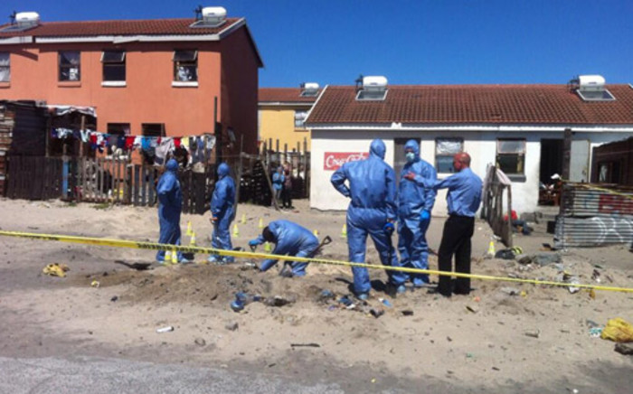 Police forensic experts in Hazmat suits digging a deep hole behind the homes of two missing Mitchells Plain girls. Picture:EWN