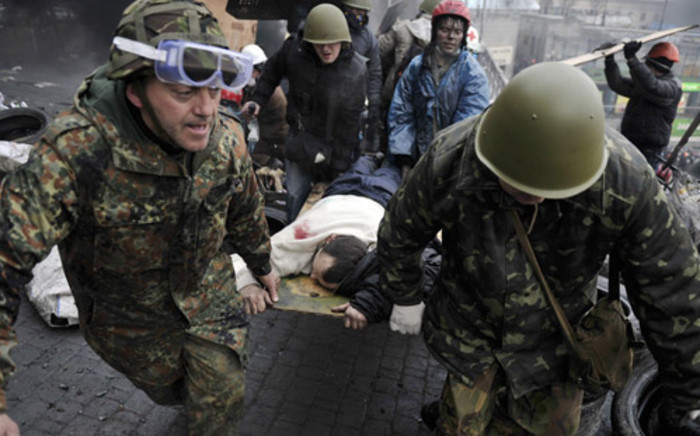 Protesters carry a wounded protester during clashes with police, after gaining new positions near the Independence square in Kiev on 20 February, 2014. Picture: AFP.