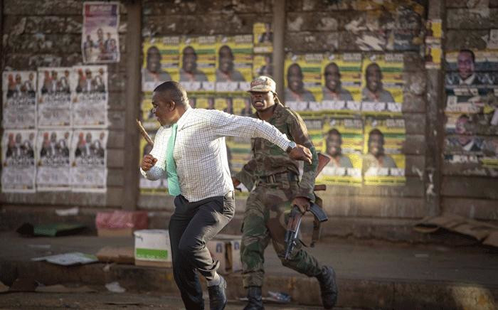 A man runs from an army officer during post-election protests in Zimbabwe on 1 August 2018. Picture: Thomas Holder/EWN