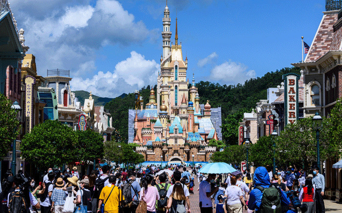 Visitors and members of the media walk in Hong Kong's Disneyland on June 18, 2020, after the theme park officially reopened following nearly five months of closure in a fresh boost for a city that has largely managed to defeat the COVID-19 coronavirus. Picture: AFP.
