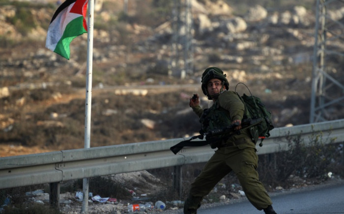An Israeli soldier hurls a smoke grenade during clashes with Palestinian youth close to the Jewish settlement of Bet El, in the West Bank city of Ramallah on 4 October 2015 after Israel barred Palestinians from Jerusalemâs Old City as tensions mounted following attacks on Israelis. Picture: AFP.