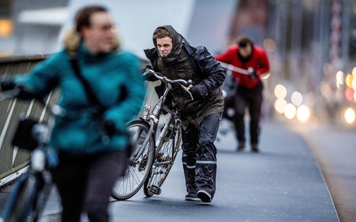 People walk with a bicycle through fierce winds in Rotterdam, on 18 January 2018, during the second western storm of the year. Picture: AFP