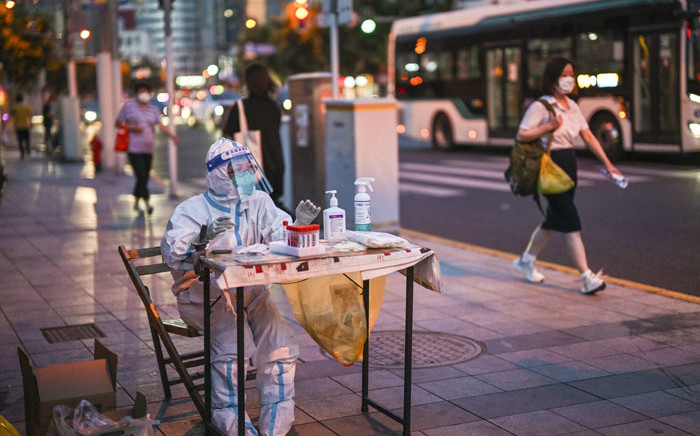 A health worker waits to test people for the COVID-19 coronavirus on a street next to a residential area in the Jing'an district of Shanghai on 5 July 2022. Picture: Hector RETAMAL/AFP