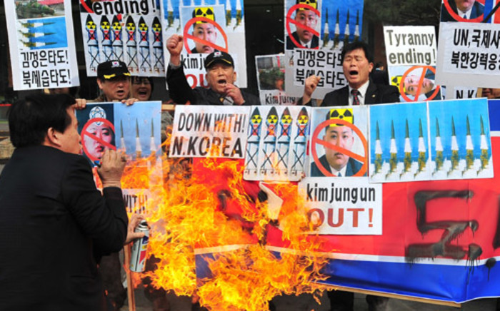 FILE: South Korean conservative activists burn a North Korean flag during a rally denouncing North Korea’s missile test-launch in Seoul on 26 March, 2014. Picture: AFP.