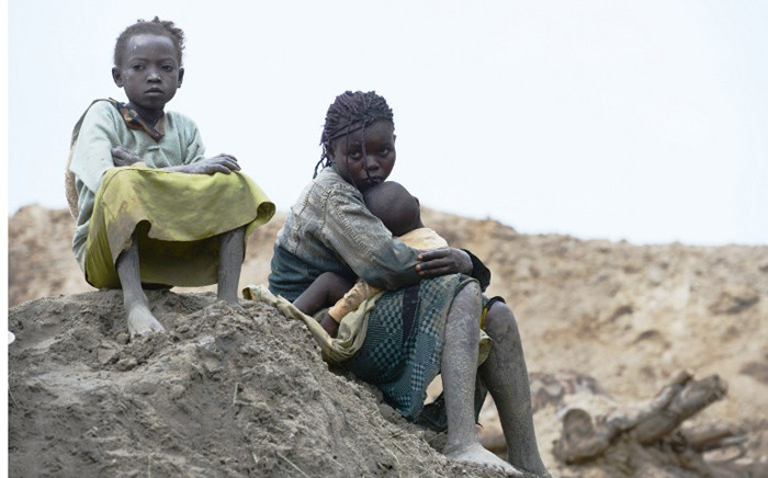 Children gold miners sit on 5 May, 2014 next to a traditional mine in the village of Gam where gold mining is the main business activity. Picture: AFP 