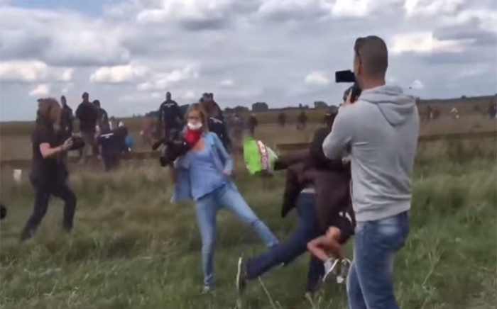 Shocking video footage has emerged of a female journalist who tripped a man carrying his son while running from Hungarian police amid the refugee crisis.