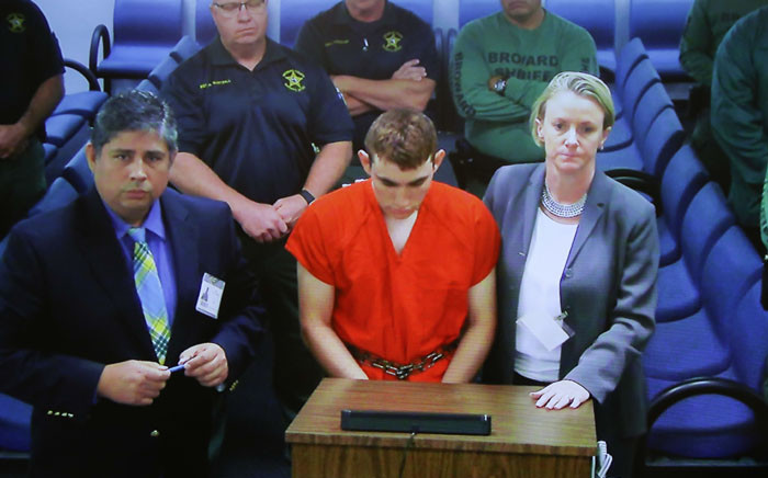 Hector Romero Asst. Public Defender (L) and Melisa McNeill, Public Defender (R) are seen on screen at the first appearance court for high school shooting suspect Nikolas Cruz (C) on 15 February 2018 at Broward County Court House in Fort Lauderdale, Florida. Picture: AFP
