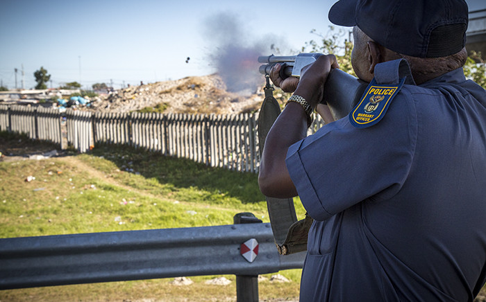A policeman fires rubber bullets at protesters on the N2 inbound outside Khayelitsha in Cape Town after land grabbers and police clashed during violent evictions. Picture: Thomas Holder/EWN
