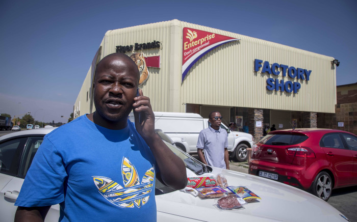 A man drops meat hampers - packets containing multiple products that cost roughly R200 - with security officials outside the Enterprise factory in Germiston. Picture: Thomas Holder/EWN