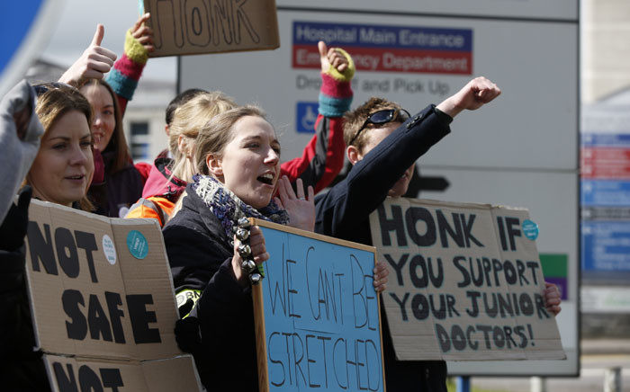 Demonstrators and junior doctors hold placards as they protest outside the Basingstoke and North Hampshire Hospital, in Basingstoke, west of London, on 26 April 2 2016, during a strike by junior doctors. Picture: AFP.
