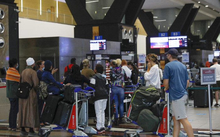Travellers queue at a check-in counter at OR Tambo International Airport in Johannesburg on 27 November 2021.