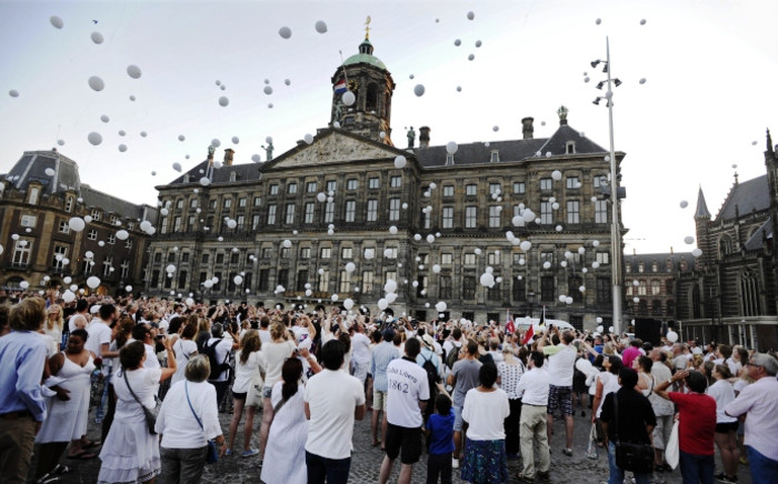 People release white balloons in the air during a silent march in memory of the victims of the downed Malaysia Airlines flight MH17, on 23 July 2014. Picture: AFP.