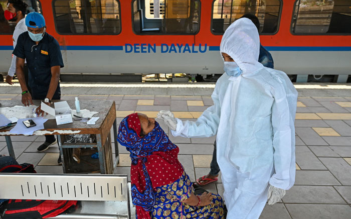 A health worker takes a nasal swab sample of a passenger for the COVID-19 coronavirus test after arriving at a railway platform on a long-distance train, in Mumbai on 14 April 2021. Picture: Punit Paranjpe/AFP