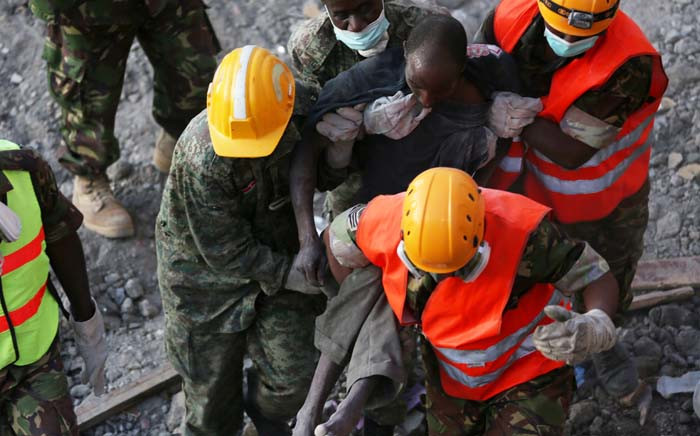 Rescue workers carry a survivor from the rubble of an apartment block, which collapsed six days previously, on 5 May 2016 in Nairobi. Picture: AFP.