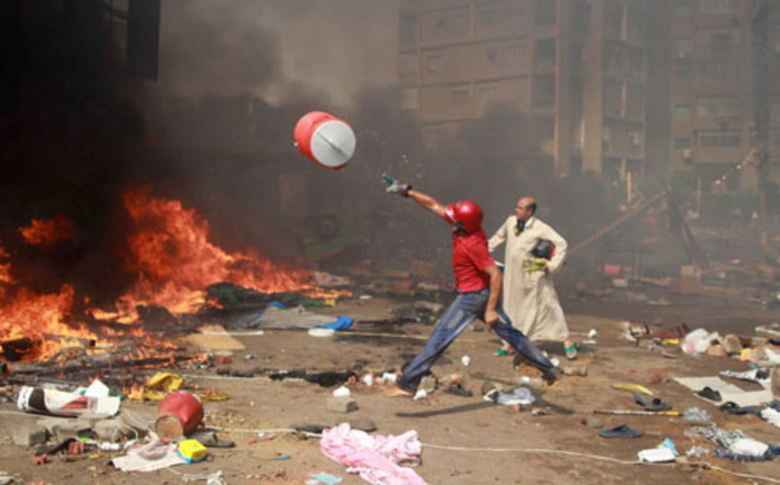 A supporter of the Muslim Brotherhood and Egypt's ousted president Mohamed Morsi throws a water container onto a fire during clashes with police in Cairo on 14 August 2013. Picture: AFP