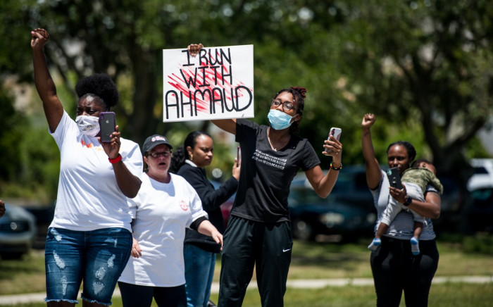 FILE: Demonstrators raise their fists at a parade of passing motorcyclists riding in honor of Ahmaud Arbery at Sidney Lanier Park on 9 May 2020 in Brunswick, Georgia. Arbery was shot and killed while jogging in the nearby Satilla Shores neighborhood on February 23. Sean Rayford/Getty Images/AFP