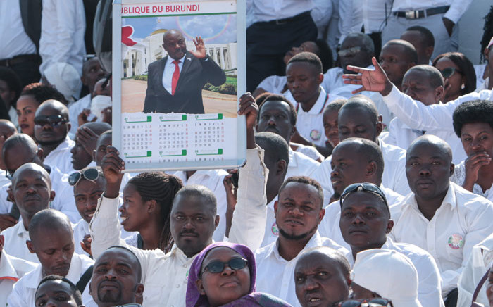A man holds a calender with the portrait of late Burundi President Pierre Nkurunziza, who died at the age of 55, as people wear white clothes while attending the national funeral at the Ingoma stadium in Gitega, Burundi, on 26 June 2020. Picture: AFP