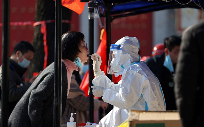 FILE: A medical worker takes a sample from a resident to be tested for the COVID-19 coronavirus in Xi'an, in China's northern Shaanxi province on 21 December 2021, after the detection of more than 40 new cases raised concerns of wider transmission ahead of a busy travel season. Picture: STR/AFP