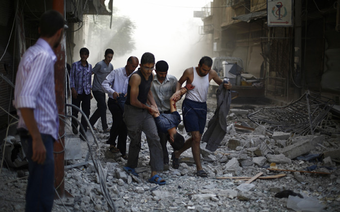 Syrians carry a wounded man following reported air strikes by Syrian government forces on the rebel-held town of Douma, east of the Syrian capital Damascus, on 2 October, 2015. Picture: AFP.