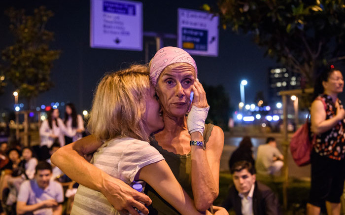 Passengers embrace outside Ataturk airport`s main entrance in Istanbul on 28 June 2016. Picture: Ozan Kose/AFP.
