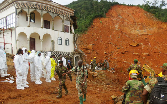 Search and rescue team members and soldiers operate near a mudslide site and damaged building near Freetown, Sierra Leone on August 15, 2017. Picture: AFP