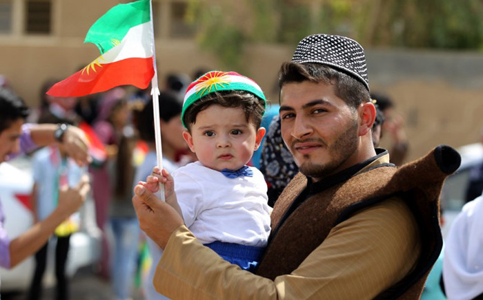 An Iraqi Kurdish man poses as he carries a child wearing the Kurdish flag on his head during a celebration in the northern city of Kirkuk on 25 September, 2017 as Iraqi Kurds vote in a referendum on independence. Picture: AFP.