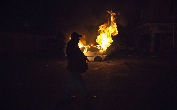 FILE: A police officer walks pass a burning car in Jeppestown during xenophobic violence on 16 April 2015. Picture: Thomas Holder/EWN