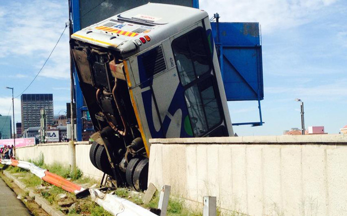 A Metrobus hangs over a bridge after the driver apparently lost control of the vehicle and crashed through the barrier wall on 25 February 2015. Picture: Masego Rahlaga/EWN.