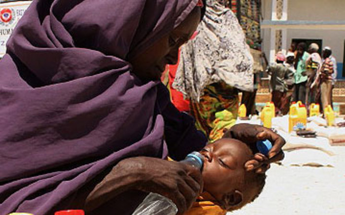 FILE: An internally displaced woman from southern Somalia gives water to her daughter at a distribution centre in Mogadishu in 2011. Picture: AFP.