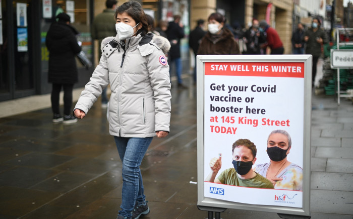 A woman walks past signage outside a pop-up vaccination centre in London on 3 December 2021. Picture: AFP