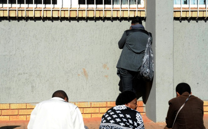 Suspect Lindray Khakhu's mother tries to avoid cameras while standing outside the Sophiatown Magistrates Court on Tuesday 5 August 2014 ahead of his appearance. Picture: Sapa. 