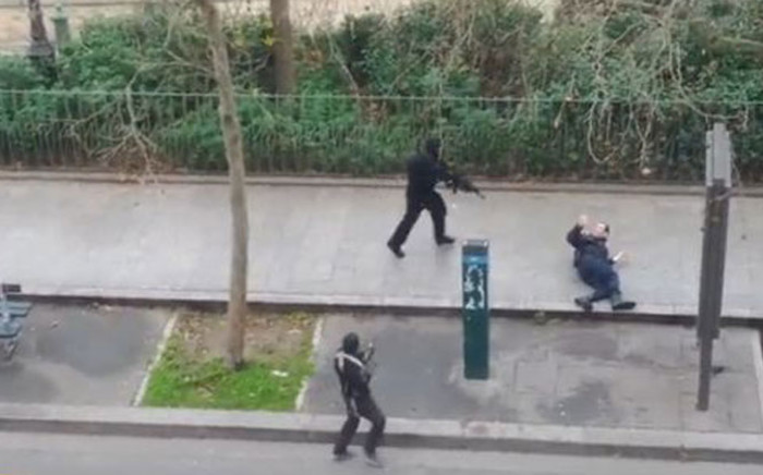 This screengrab from a video posted online shows armed men approaching a man who was shot moments before on a Paris street near the Charlie Hedbo offices on 7 January 2015. Seconds later the gun men shoots the victim a second time.