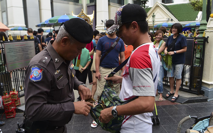 A Thai policeman searches a visitor's bag at the Erawan Shrine in the centre of Bangkok on August 13, 2016 as authorities increase security following a new string of bomb attacks in Thailand. Picture: AFP.