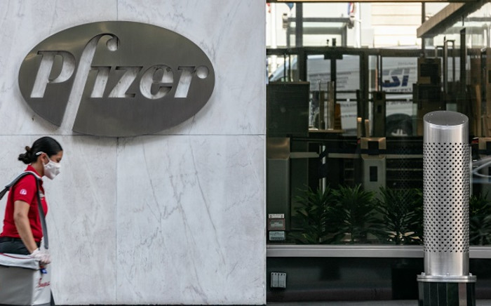 FILE: A pedestrian wearing a protective mask walks past Pfizer Inc headquarters on 22 July 2020 in New York City. Pfizer and German biotechnology firm BioNTech have agreed to supply the US government with 100 million doses of coronavirus vaccine under a $1.95 billion deal. Picture: AFP.
