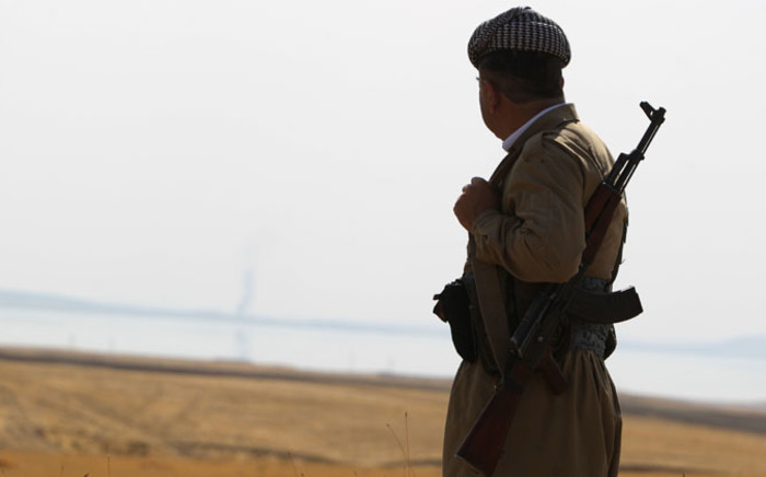 FILE: A Kurdish peshmerga fighter looks at smoke rising in the horizon following US airstrikes targeting Islamic State (IS) militants at Mosul Dam on 18 August 2014. Picture: AFP