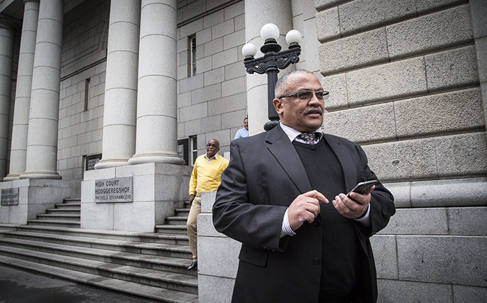 General Arno Lamoer checks his phone outside the Western Cape High Court for his pre-trial conference. Lamoer and three police officials and the Dawjee men face 109 charges between them, including fraud and corruption. Picture: Thomas Holder/EWN.