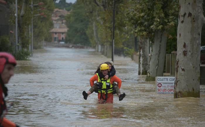 A firefighter helps a youngster in a flooded street during rescue operation following heavy rains that saw rivers bursting banks on 15 October 2018 in Trebes, near Carcassone, southern France. Picture: AFP
