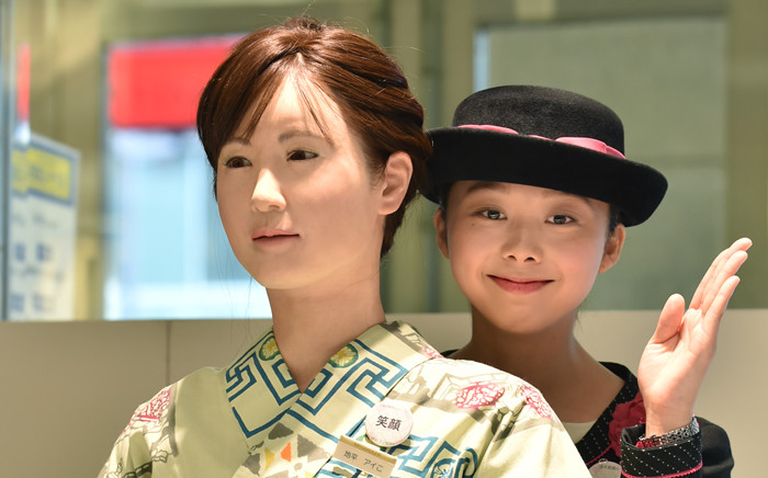 A department store employee poses with humanoid ChihiraAico (L) clad in a Japanese kimono in Tokyo on 20 April, 2015. Picture: AFP.