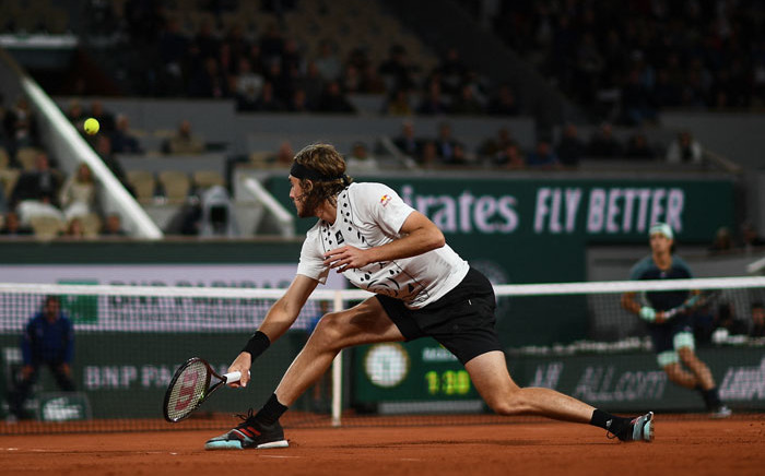 Greece's Stefanos Tsitsipas (L) plays a backhand return to Italy's Lorenzo Musetti (R) during their men's singles match on day three of the Roland-Garros Open tennis tournament at the Court Philippe-Chatrier in Paris on 24 May 2022. Picture: Christophe ARCHAMBAULT / AFP
