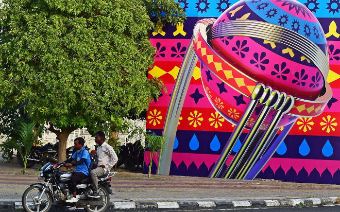 Motorcyclists ride past a billboard installed outside the Narendra Modi Stadium, ahead of the 2023 ICC men's cricket World Cup, in Ahmedabad on 30 September 2023. The opening match on 5 October between champions England and New Zealand, as well as the final on 19 November are being staged at Ahmedabad's Narendra Modi stadium, named after the prime minister, the world's biggest cricket arena boasting a capacity of over 130,000. Picture: Sam PANTHAKY / AFP