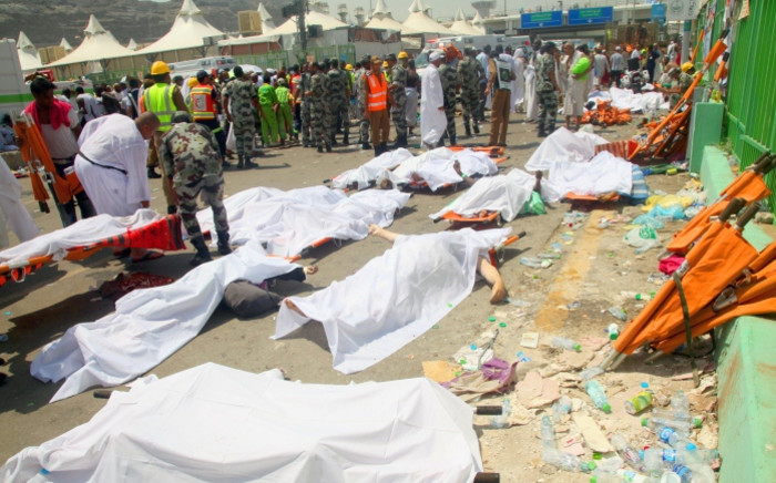 Saudi emergency personnel and haj pilgrims stand near bodies covered in sheets at the site where at least hundred were killed and wounded in a stampede in Mina, near the holy city of Mecca, at the annual haj in Saudi Arabia on 24 September 2015. Picture: AFP.